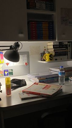 an office desk with books, water bottle and lamp