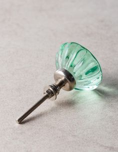 a small green glass object with a screw in it