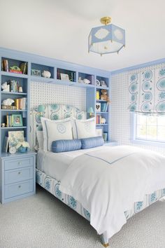 a blue and white bedroom with bookshelves on either side of the headboard