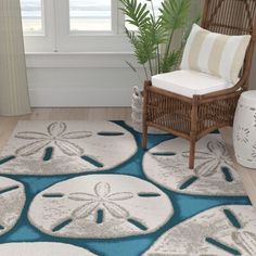 a blue and white rug with sand dollars on it in a room next to a chair