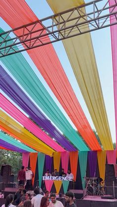 a group of people standing on top of a stage under colorful draping above them