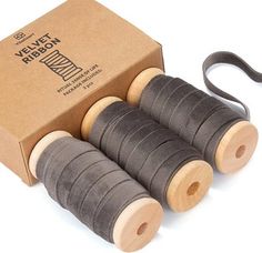 four spools of thread sitting in front of a cardboard box with two handles