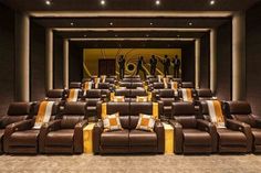 an empty movie theater with brown leather seats and yellow striped throw pillows on the floor