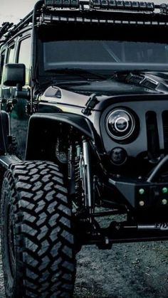 the front end of a black jeep with its lights on