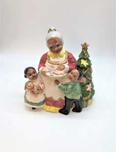 a figurine of an elderly woman and two children with a christmas tree in the background