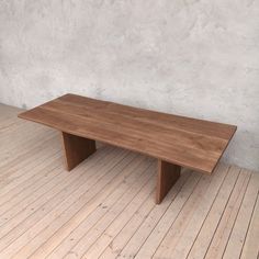 a wooden table sitting on top of a hard wood floor next to a white wall