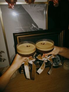 two people holding onto some cakes in front of a painting on a table with candles