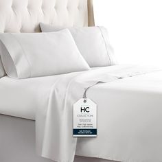 a bed with white sheets and pillows on it