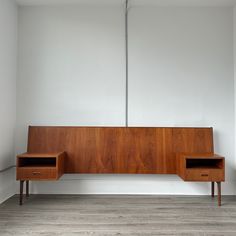 a wooden bench sitting next to a white wall with two drawers on each side and a lamp hanging from the ceiling