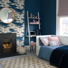 a bedroom with blue walls, white furniture and a pink chair in front of the fireplace