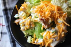 a black plate topped with lettuce and cheese