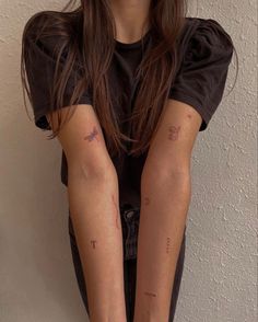 a woman with her arm covered in tattoos sitting on the ground next to a wall