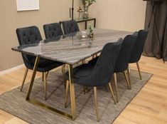 a dining room table with black chairs and a rug on the floor in front of it