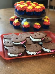 some cupcakes are on a red tray and there is a cake in the background