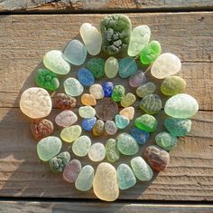 several different colored rocks arranged in a circle on a wooden surface, with small pebbles scattered around them