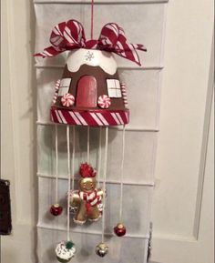 a gingerbread house hanging on a wall with candy canes and candies around it