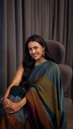 a woman sitting in a chair wearing a green and brown sari