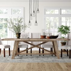 a dining room table with white chairs and plants