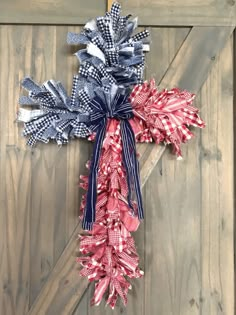 a cross made out of red, white and blue ribbons hanging on a wooden door