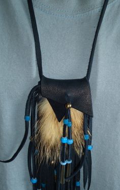 a black leather bag with blue trim and tassels hanging from it's side