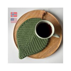 a green knitted dishcloth on a wooden plate with a cup of black coffee