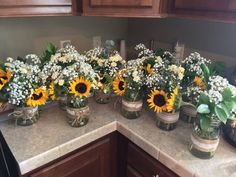 sunflowers and baby's breath are arranged in mason jars on the kitchen counter