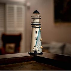 a white and blue lighthouse sitting on top of a wooden table next to a window