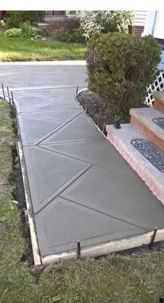 a concrete walkway with steps leading up to the front door and back porch area, surrounded by grass