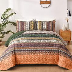 a bed with an orange and green bedspread