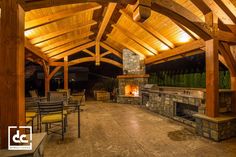 a covered patio with tables and chairs around an outdoor fireplace