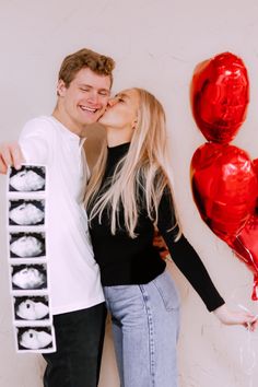 a man and woman standing next to each other with balloons in the air behind them