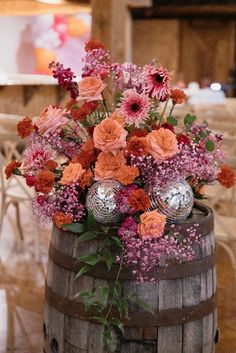 a wooden barrel filled with lots of flowers and disco ball decorations on top of it