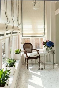 a chair sitting on top of a white floor next to a window filled with plants