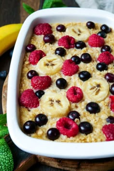 an oatmeal dish with berries, bananas and blueberries in it on a table