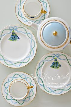 four tea cups and saucers decorated with blue, green and gold trimmings