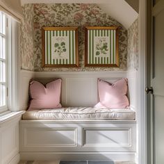 two framed pictures hang on the wall above a bench in a room with floral wallpaper