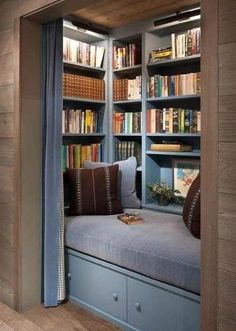 a window seat in the corner of a room with bookshelves and shelves full of books