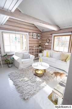 a living room filled with white furniture and wooden walls