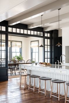 a kitchen with black and white walls, wooden flooring and bar stools in front of an island