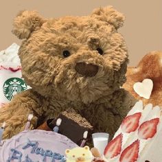 a brown teddy bear sitting next to two cakes