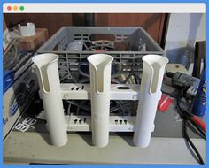 three white plastic utensils sitting in front of a dishwasher with tools nearby