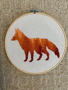 a cross stitch fox is shown on the wall