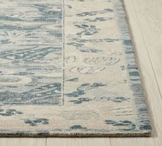 a blue and white area rug on a wooden floor with light colored wood planks