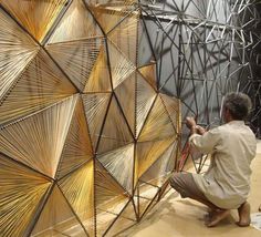 a man working on an art piece in a room filled with metal wire and wood