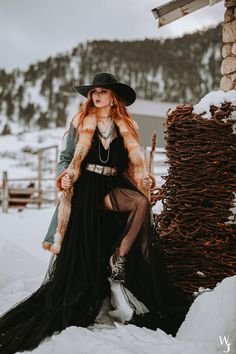 a woman sitting on top of a pile of hay in the snow