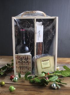 a bottle of wine, cheese and other items in a gift box on a wooden table