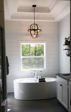 a white bath tub sitting under a window in a bathroom