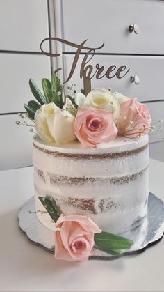 a three layer cake with pink and white flowers on top