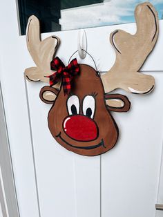 a door hanger with a reindeer head painted on it's side and a red nose