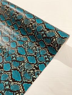 a blue and black snake skin pattern on a white sheet or bed spread with the top part of it folded up